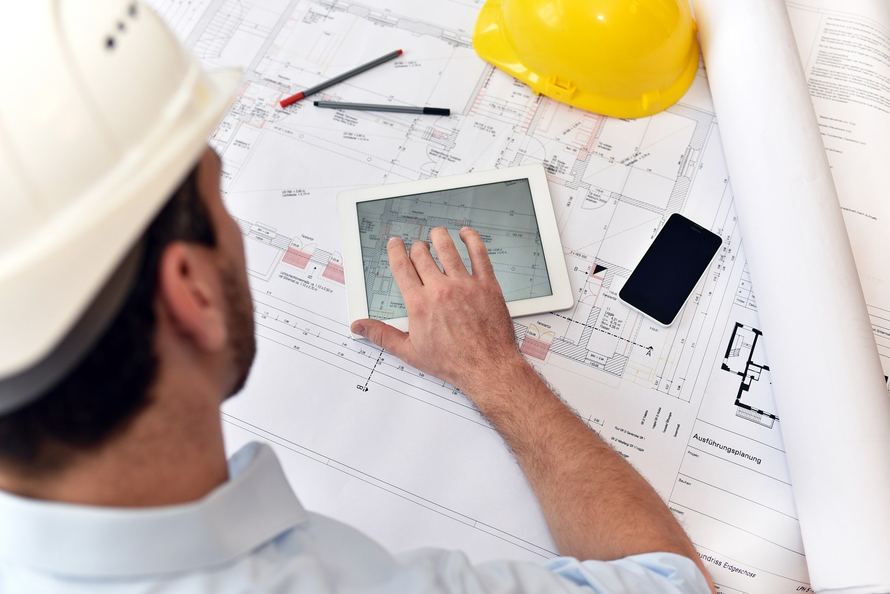 Planung und Entwicklung im Bauwesen - Architekt mit Tablet und techn. Zeichnung am Arbeitsplatz
